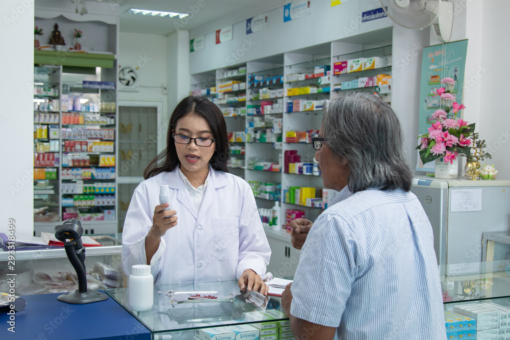 Young Asian attractive female pharmacist explaining details information of medicine products, apothecary pay attention listen illness client male, giving prescription to senior man
