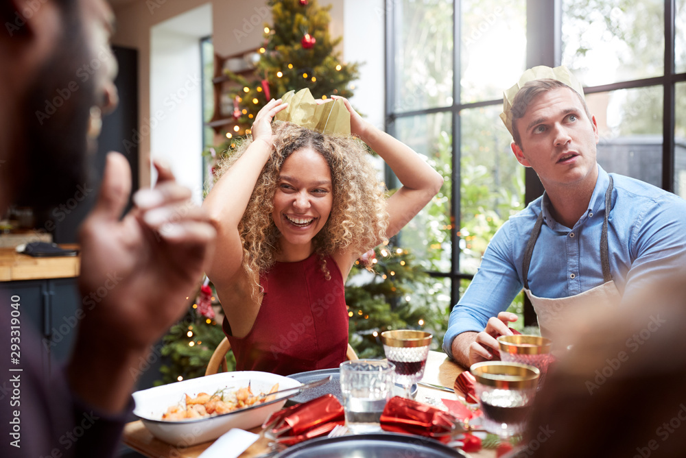 Group Of Friends Sitting Around Dining Table At Home As Christmas Dinner Is Served Group Of Friends Sitting Around Dining Table At Home As Christmas Dinner Is Served