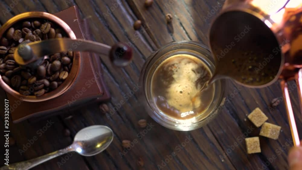 Freshly brewed coffee from cezve is poured into a coffee cup. Steam comes out of the cup, an old coffee grinder is in the composition. 4K video. Freshly brewed coffee from cezve is poured into a coffee cup. Steam comes out of the cup, an old coffee grinder is in the composition. 4K video.