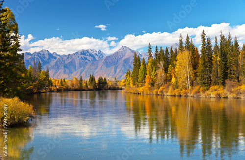 Siberian autumn beautiful landscape with the Eastern Sayan Mountains. Yellowed trees are reflected in the Irkut River. Baikal region, Buryatia, Tunka Valley