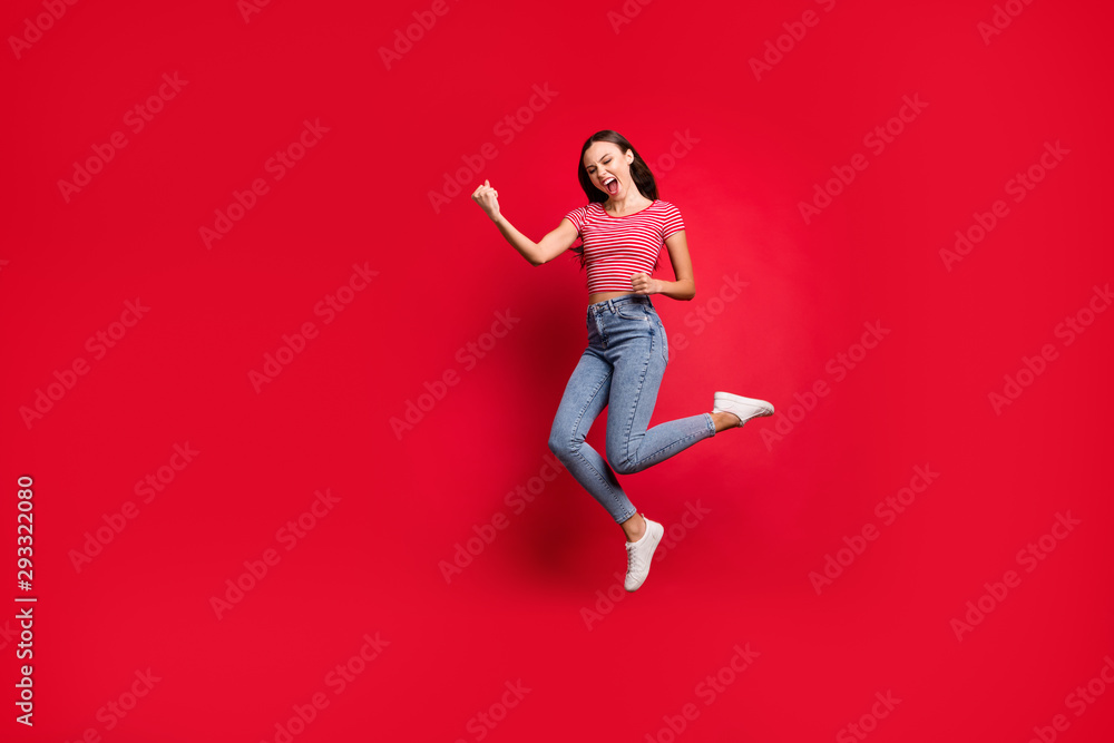 Full length body size photo charming cute fascinating nice girlfriend wearing jeans denim striped t-shirt winning something and rejoicing with it while isolated with red background