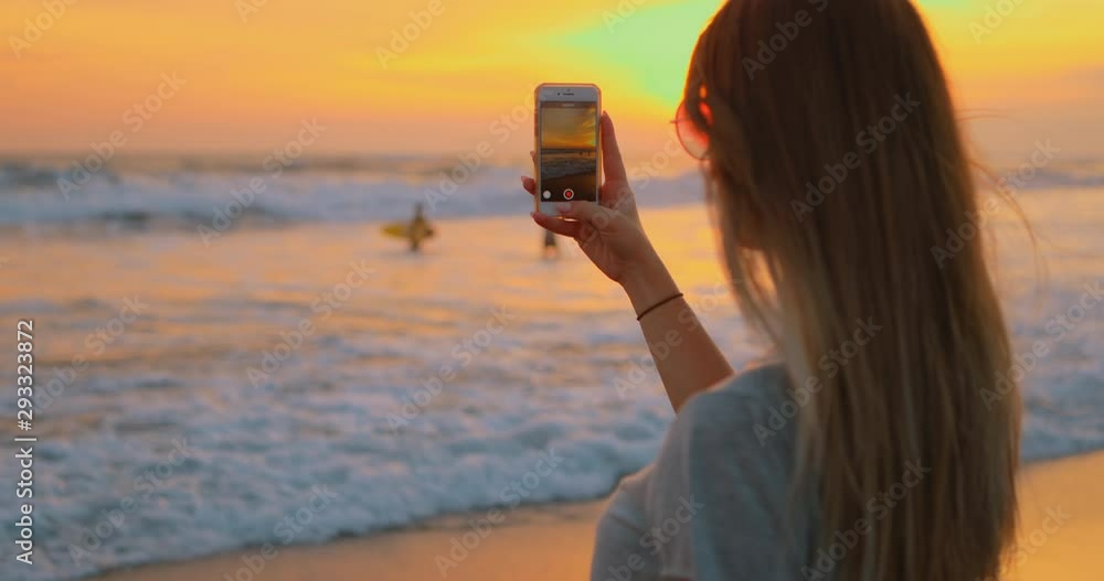 Young female felling fun and free on beach at sunset. Carefree girl on tropical beach takes photos of nature on a smartphone at golden sunrise. Happy tourist woman on summer vacation. 5g Internet. Young female felling fun and free on beach at sunset. Carefree girl on tropical beach takes photos of nature on a smartphone at golden sunrise. Happy tourist woman on summer vacation. 5g Internet.