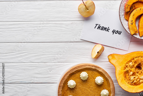 top view of pumpkin pie, ripe apples and thank you card on wooden white table