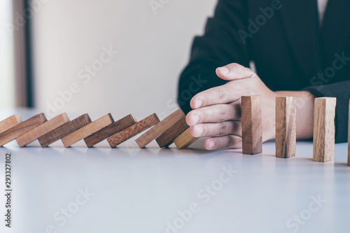 Risk and Strategy in Business, Image of hand stopping falling collapse wooden block dominoes effect from continuous toppled block, prevention and development to stability