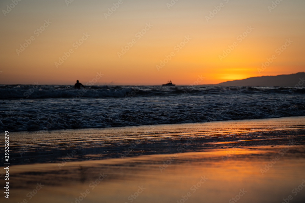 Surfer waiting for the wave in the sunset near the ocean shore in sunny California
