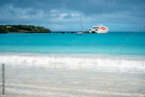 Pier and ferry boat at Kuto Bay on a beautiful but slightly overcast morning at Isle of Pines in New Caledonia, South Pacific Ocean.