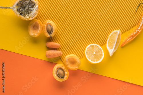 top view of fresh fruits and vegetables on yellow and orange background with copy space photo