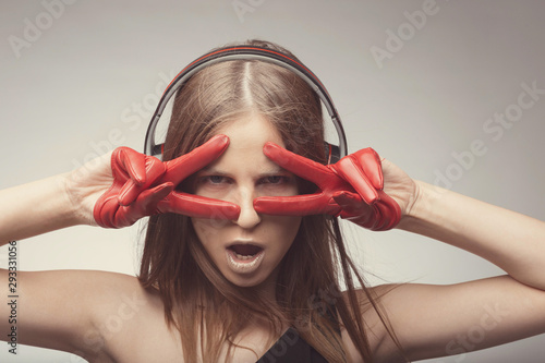 Joyable attractive fashion pretty girl listening music with headphones, wearing red gloves, take pleasure with song. Lifestyle woman concept photo