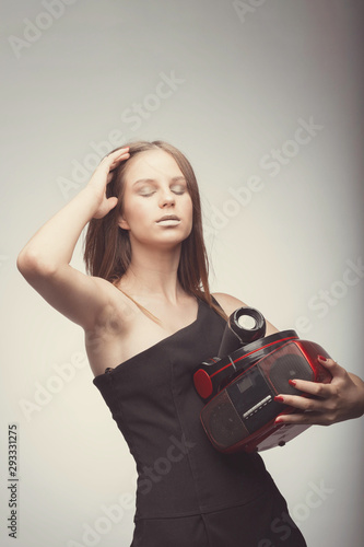 Joyable attractive fashion pretty girl listening music with headphones, speaker, record player, holding thm in hands and wearing red gloves, take pleasure with song. Lifestyle woman concept photo