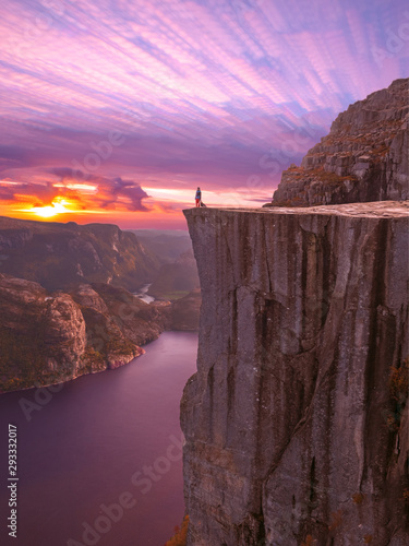 frau mit hund bei sonnenuntergang auf dem preikestolen