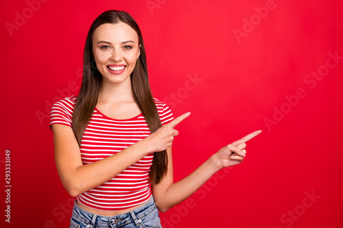 Photo of confident beautiful pretty sweet girl wearing jeans denim pointing at copyspace away from her while isolated with red background