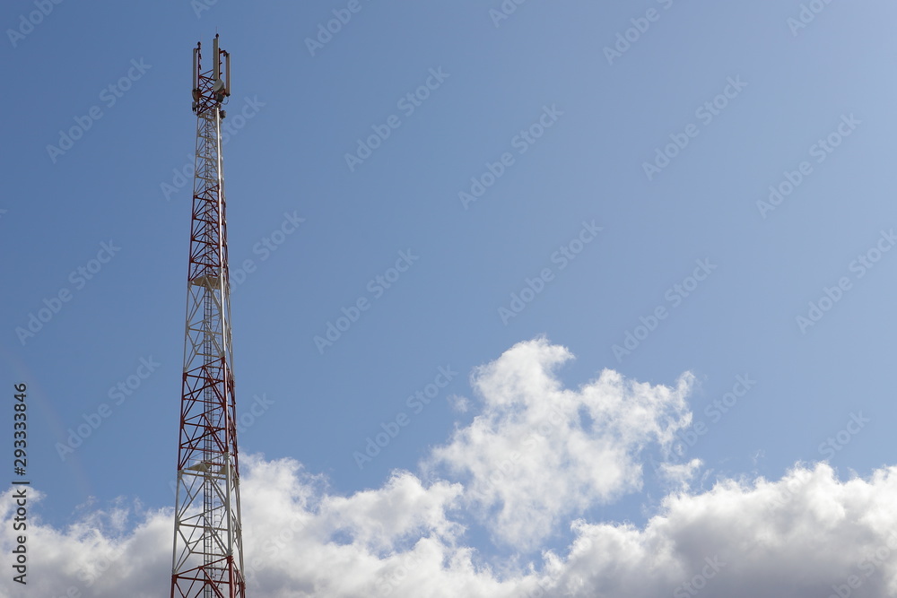 Telecommunications tower on light blue sky background and white club clouds Telecommunications tower on light blue sky background and white club clouds