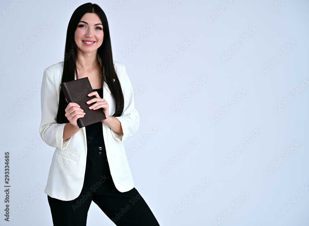 Portrait of a pretty brunette girl with good makeup with long hair on a white background in a light business suit. He stands in different poses with emotions with a folder in his hands. Portrait of a pretty brunette girl with good makeup with long hair on a white background in a light business suit. He stands in different poses with emotions with a folder in his hands.