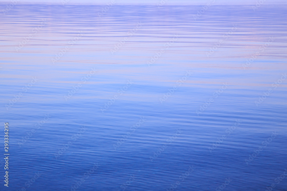 Clear water texture in blue and orange. Background of the ocean and the sea backlit by the sun. Soft waves. Natural water Clear water texture in blue and orange. Background of the ocean and the sea backlit by the sun. Soft waves. Natural water