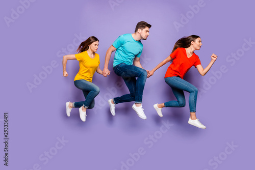Full length size body photo of concentrated with funny facial expression group of three hipsters running away do not look back isolated violet background © deagreez