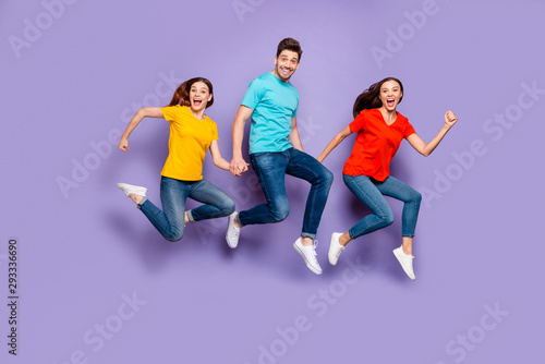 Full length size body photo of three excited cheerful crazy unstoppable actively moving victorious successful freelancers group of millennials holding hands isolated violet background