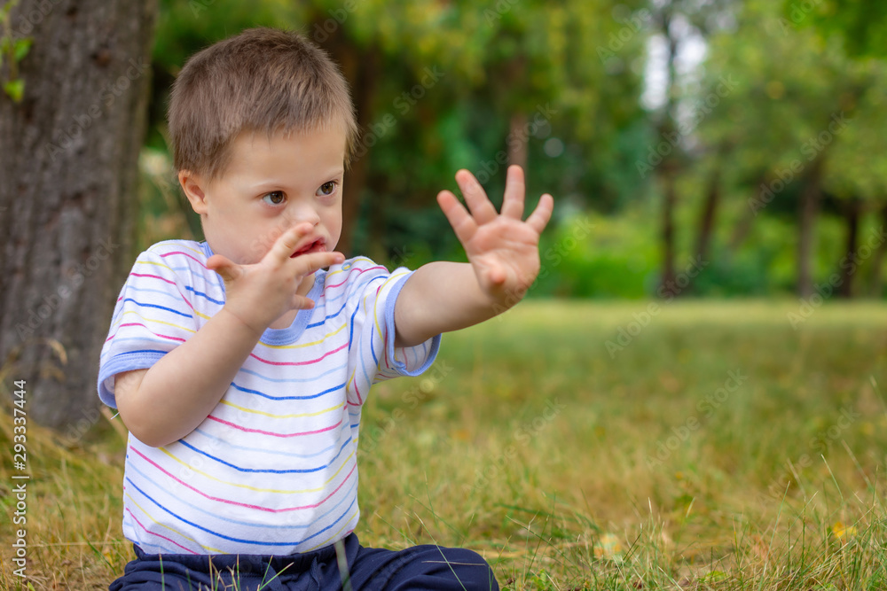Cute small boy with Down syndrome playing in summer day on nature Cute small boy with Down syndrome playing in summer day on nature