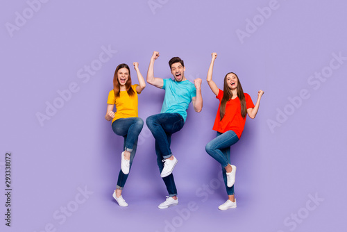 Full body length size photo of cheerful excited ecstatic positive lucky company of fellows having fun raising fists up isolated over violet background