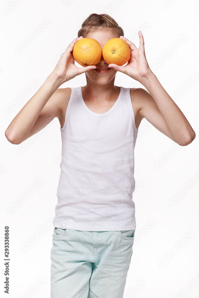 A young guy in a white shirt, closes his eyes with oranges, laughs, pampers, plays. On a white background in the studio. Emotions, fruit, lifestyle, happy childhood. A young guy in a white shirt, closes his eyes with oranges, laughs, pampers, plays. On a white background in the studio. Emotions, fruit, lifestyle, happy childhood.