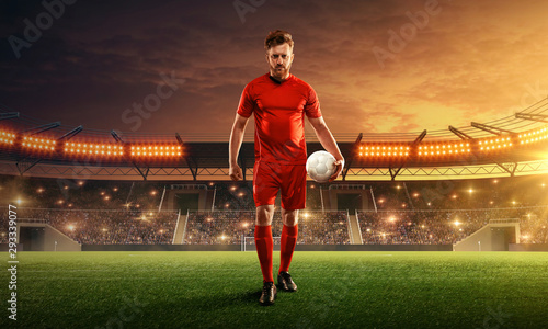 Soccer player on a floodlit and crowded stadium with a ball. Dramatic night sky