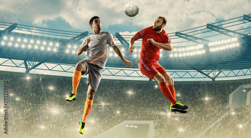 Soccer players fight for a ball in air. Jump shot. Soccer field with tribunes © TandemBranding