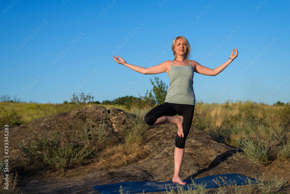 Young woman doing yoga exercises outdoors. Young woman doing yoga exercises outdoors.