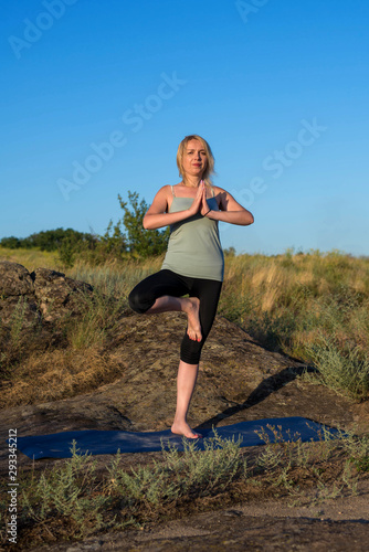 Young woman doing yoga exercises outdoors.