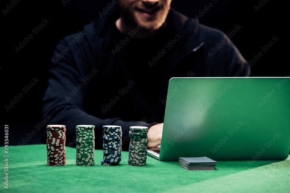 cropped view of happy man using laptop near playing cars isolated on black cropped view of happy man using laptop near playing cars isolated on black