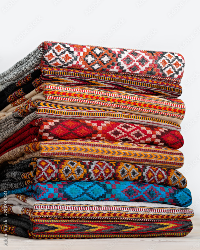 Woolen blankets, stoles folded and stacked in stack of several rows. Beautiful texture and colors of products create amazing effects. Studio shot. Woolen blankets, stoles folded and stacked in stack of several rows. Beautiful texture and colors of products create amazing effects. Studio shot.