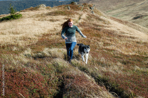 Girl runs with dog. The Husky are black and white. Hiking in the mountains. Carpathian Mountains