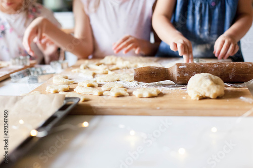 Children hands are cooking Christmas gingerbread cookies in cozy home kitchen. Kids preparation holiday food for family. Little girls bake homemade pastries. Children chef concept.