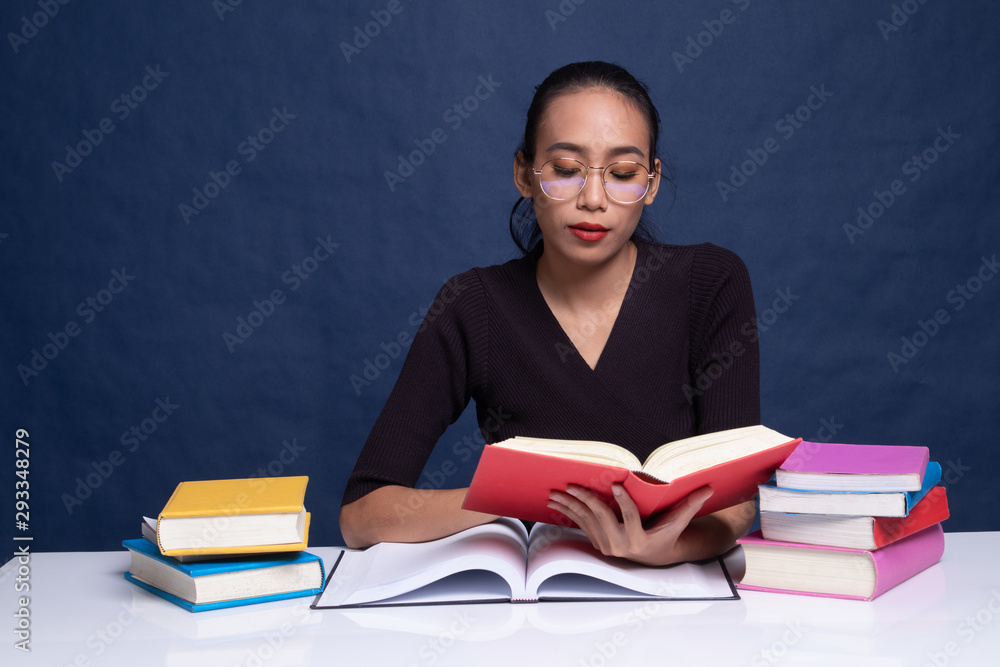 Young Asian woman read a book with books on table. Young Asian woman read a book with books on table.