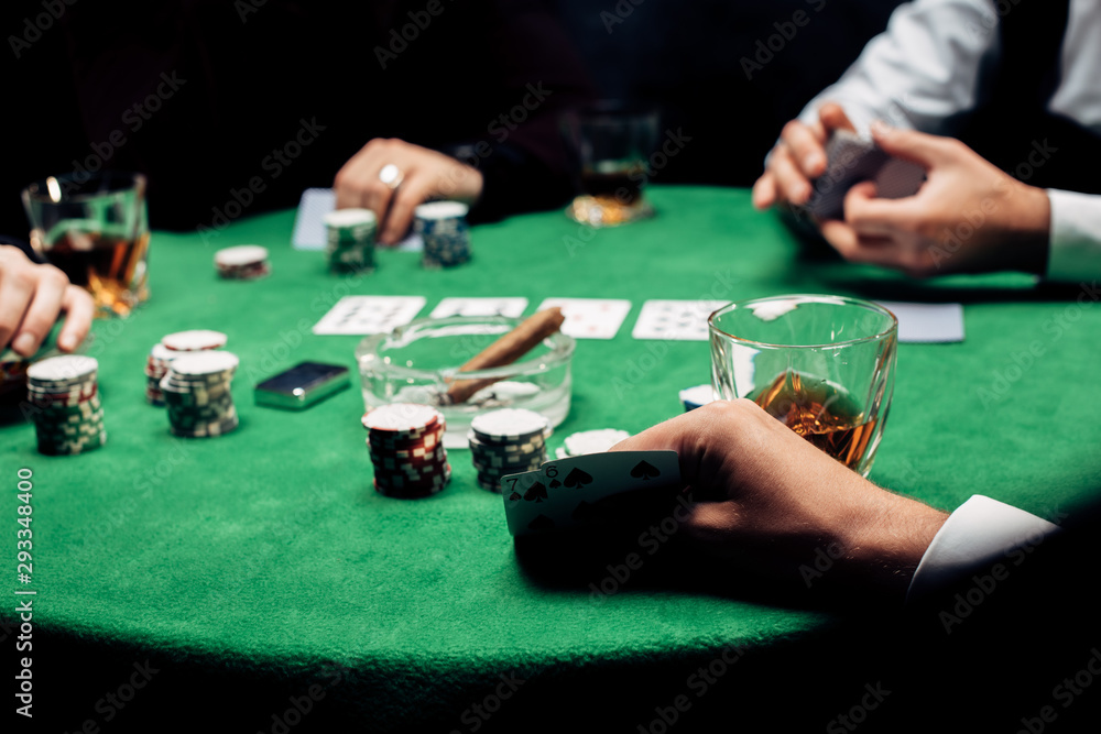 cropped view of man holding playing cards near croupier isolated on black cropped view of man holding playing cards near croupier isolated on black