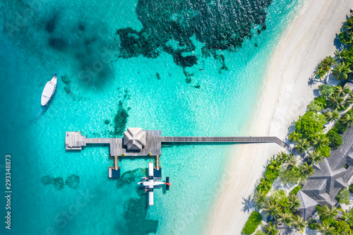 Aerial view of seaplane wooden jetty and water villa and blue sea background in Maldives island. Aerial landscape of Maldives coast