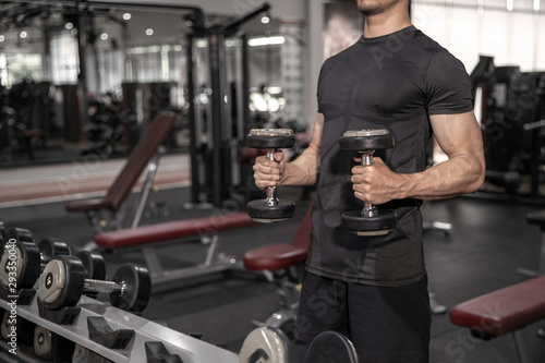 close up of fitness man's hand exercising biceps in gym with dumbbells in the gym
