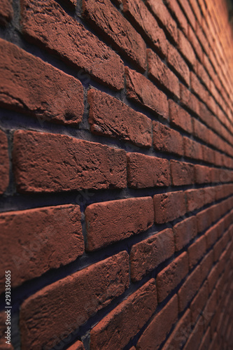 An orange brick wall at an angle with bokeh. Stone blurred background. Closeup vertical photo.
