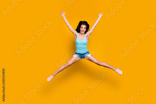 Full length body size photo of cheerful cute ecstatic rejoicing girl having won competition and jumping up with happiness doing splits isolated over vivid color background