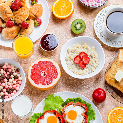 Continental breakfast with cereal, fried eggs, croissants, fruits and drinks on textured table, copy space