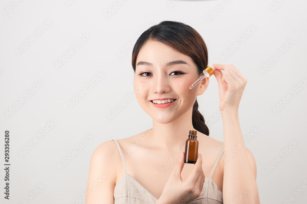 Young amazing woman posing isolated over white background holding oil drop serum. Young amazing woman posing isolated over white background holding oil drop serum.