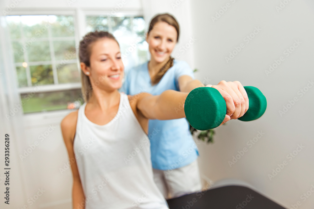 A Modern rehabilitation physiotherapist at work with client. Working on shoulder with dumbell A Modern rehabilitation physiotherapist at work with client. Working on shoulder with dumbell