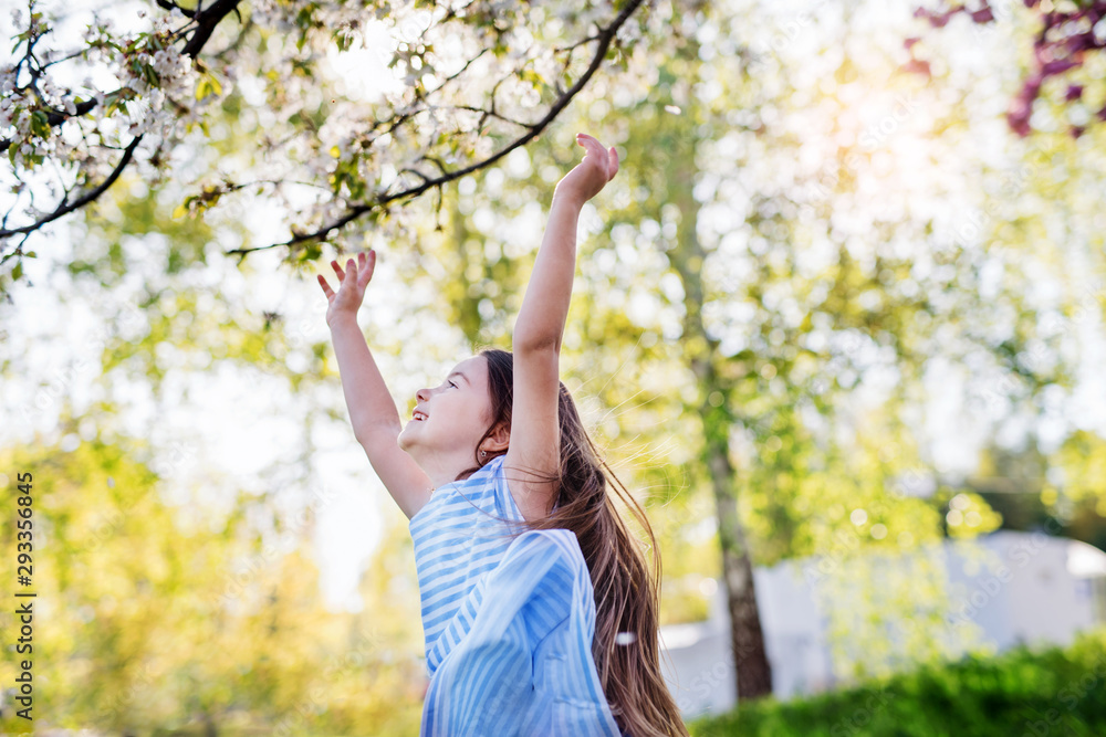 A cheerful small girl running outside in spring nature. A cheerful small girl running outside in spring nature.