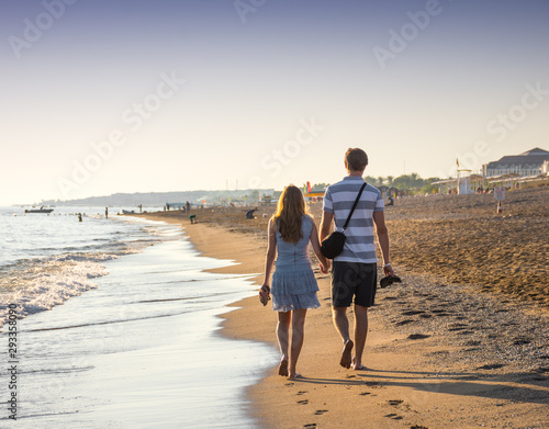 Happy romantic couple enjoying sunset walk on the beach