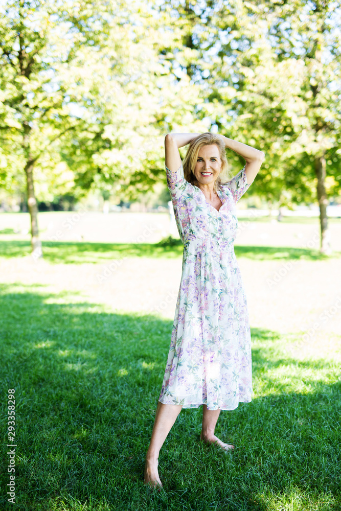 Naklejka premium Attraktive älterte Frau im Sommerkleid im Park