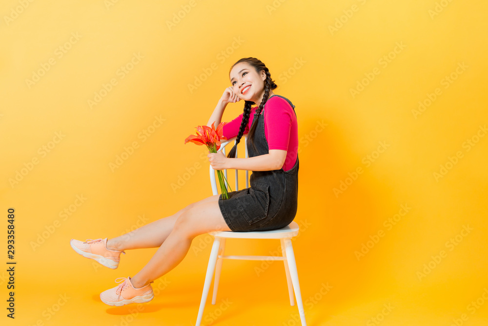 Portrait of happy beautiful Asian woman with bouquet of flowers on yellow background Portrait of happy beautiful Asian woman with bouquet of flowers on yellow background