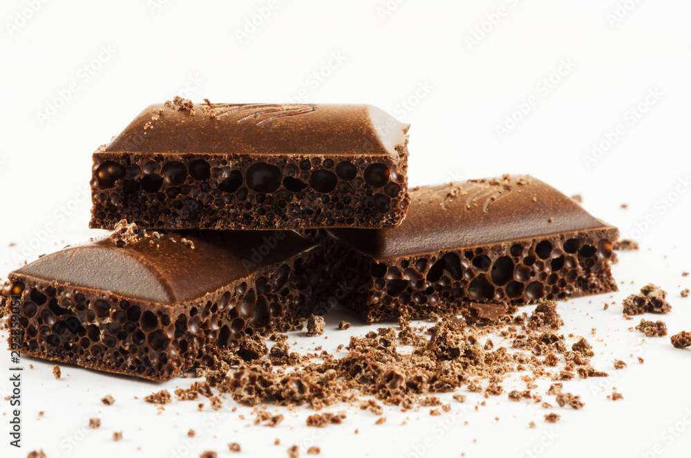 Slices of aerated chocolate and chocolate crumb on a white background Slices of aerated chocolate and chocolate crumb on a white background
