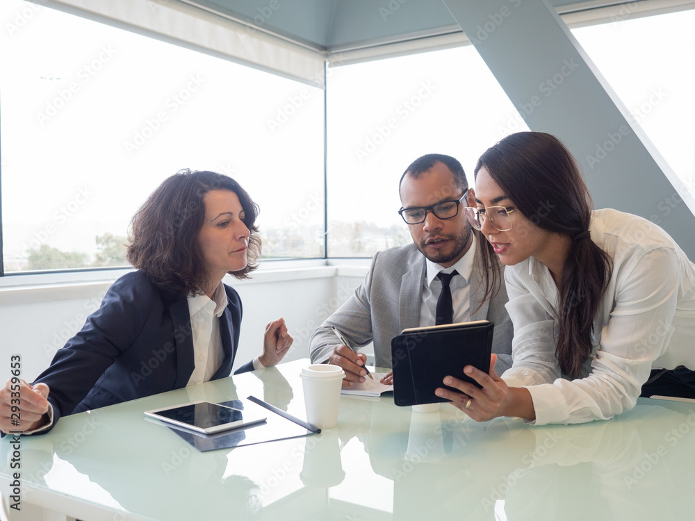 Multiethnic business people with digital tablet. Professional business team working at table with gadgets and papers. Brainstorming concept