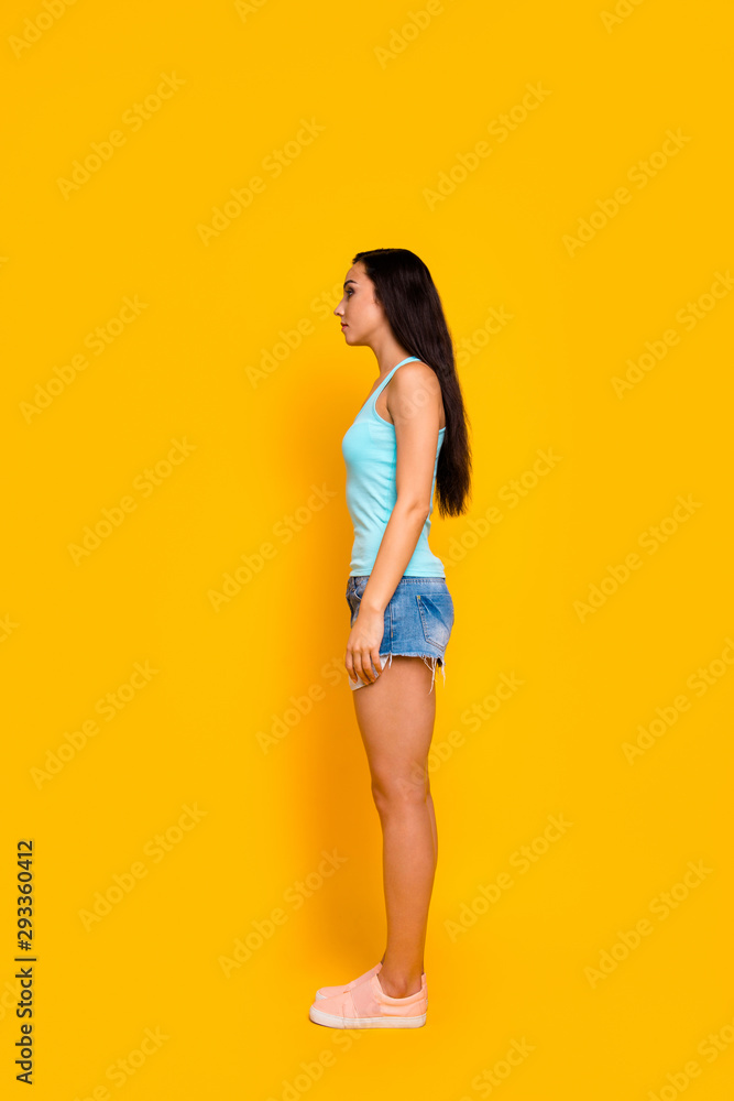Vertical full length body size side profle photo of girl staring away wearing jeans denim shorts sneakers isolated over bright color background Vertical full length body size side profle photo of girl staring away wearing jeans denim shorts sneakers isolated over bright color background