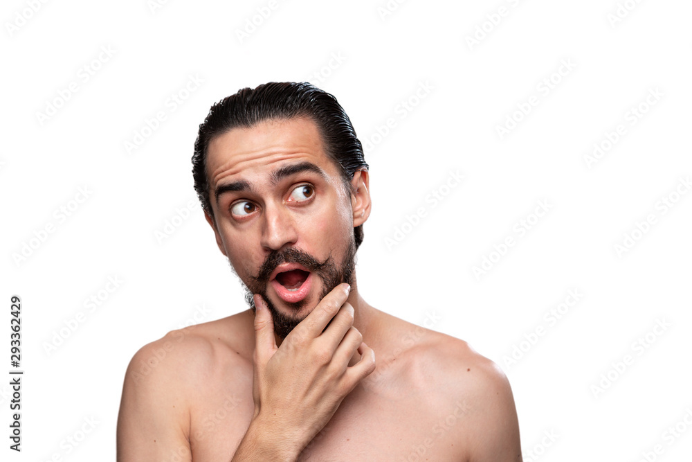 Fototapeta premium Thoughtful handsome bearded man with mustaches standning bare isolated over white background and looking at the right upper corner. Concept of morning treatment. Place for advertising