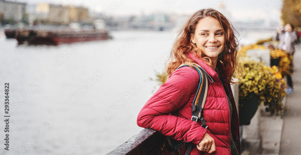 Fototapeta premium Portrait Beautiful charming young funny happy girl with red curly hair and on the promenade in the autumn park
