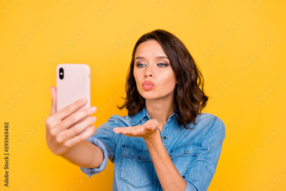 Close up photo of romantic lady blogger use her cell phone to take selfie for her blogs on summer holidays send air kisses for followers wear trend outfit isolated over yellow color background Close up photo of romantic lady blogger use her cell phone to take selfie for her blogs on summer holidays send air kisses for followers wear trend outfit isolated over yellow color background